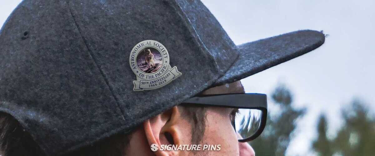 Astronomical Society of the Pacific 50th Anniversary offset printed hat pin featuring Apollo moon landing photo, worn on a gray cap