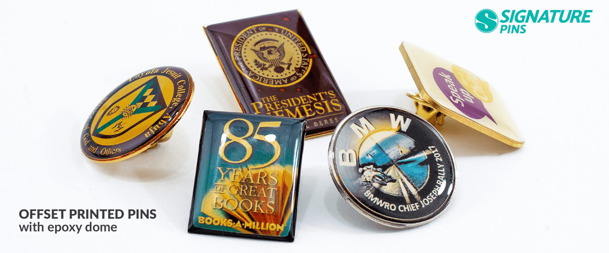 Assortment of offset printed pins with epoxy dome including presidential seal pin, 85 Years of Great Books pin, and BMW aerospace pin
