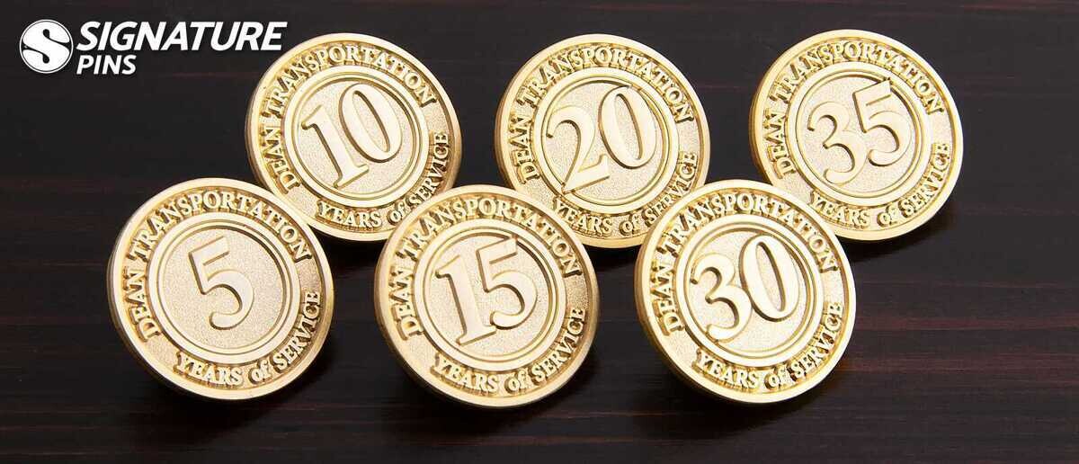 Six gold die struck Dean Transportation years of service pins for 5, 10, 15, 20, 30, and 35 years